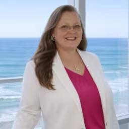 headshot of Jill Bumgarner, wearing a white blazer with a pink shirt