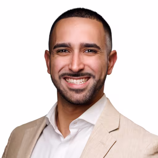 headshot of Ariel Carballo, wearing a tan suit with a white shirt