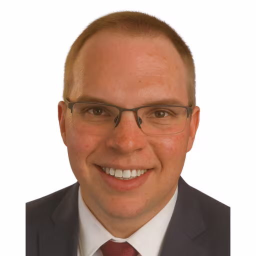 headshot of Ben Gaines wearing white shirt, red tie, and dark gray suit coat