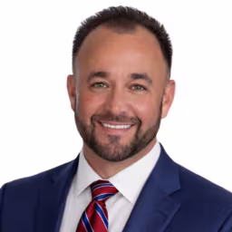 Headshot of Bobby Stines, wearing a dark blue suit with a red tie