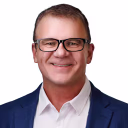 headshot of Brent Tye, wearing a dark blue suit and white shirt