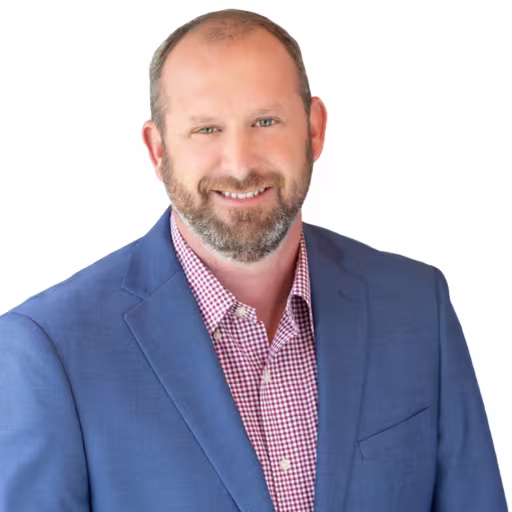 Headshot of Brian Bailey wearing red and white checkered dress shirt and blue suit coat with white background