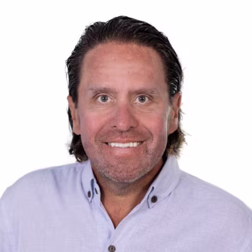 Headshot of Brian Logie wearing light blue button up shirt with white background