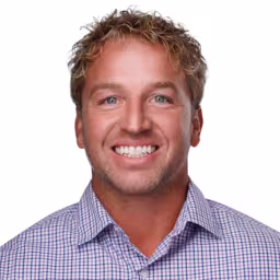 Headshot of Chad Seeling wearing white, blue, and purple checkered shirt with white background
