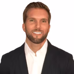 Headshot of Charlie Davis wearing white dress shirt and black suit coat with white background