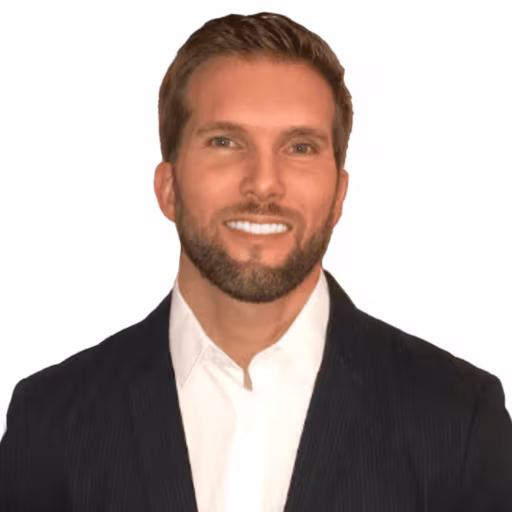 Headshot of Charlie Davis wearing white dress shirt and black suit coat with white background