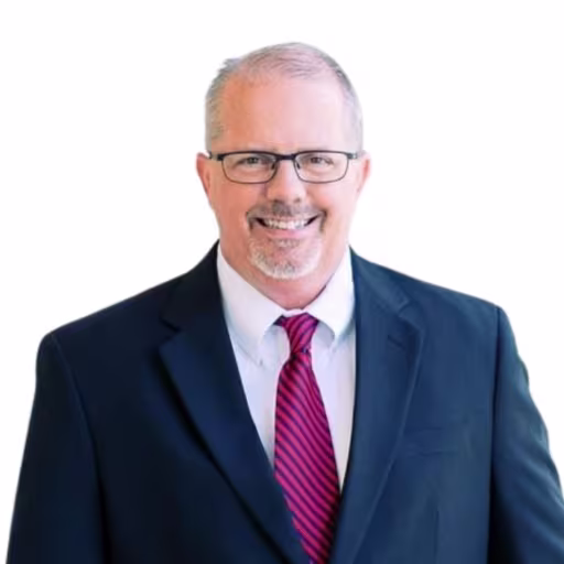 headshot of Chip Brother, wearing a black suit with a red tie
