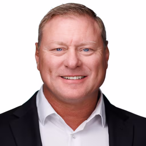 headshot of Chris Barnes, wearing a black suit with a white shirt.