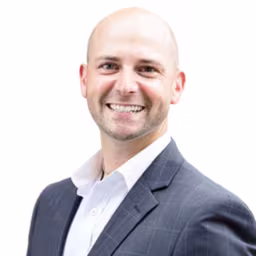 headshot of Chris Byrnes, wearing a dark grey suit and a white shirt