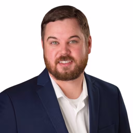 headshot of Clay Brown, wearing a dark blue suit and white shirt