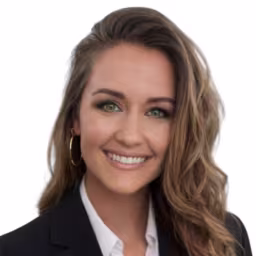 Headshot of Courtney Love, wearing a black blazer and white shirt