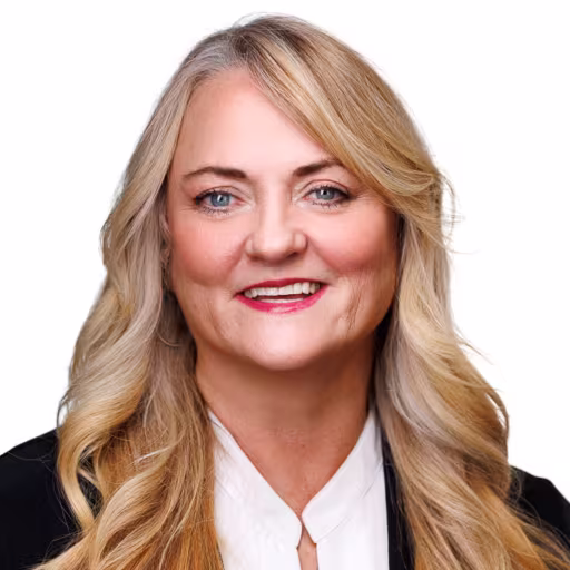 headshot of Dede Hanka, wearing a black suit with a white blouse