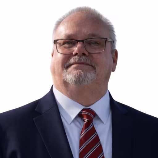 headshot of Dennis Marshall, wearing a black suit with a red tie