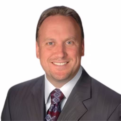 headshot of Drew Stark, wearing a grey suit and purple tie