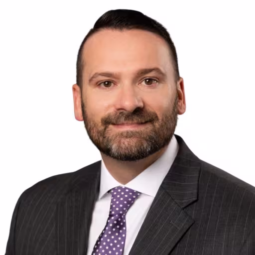 Headshot of Ed Charleson, wearing a black suit with a purple pinstripe tie.