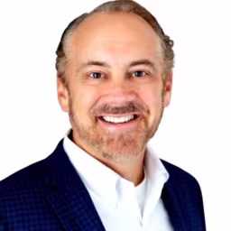 headshot of Eric Wagner, wearing a black blazer with a white shirt