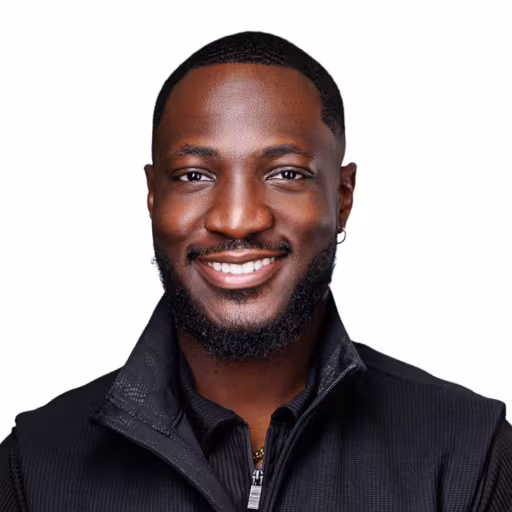 headshot of Frank Onyeaghala, wearing a black shirt with a black vest