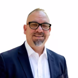 headshot of Gabe Romo, wearing a dark blue blazer and white shirt