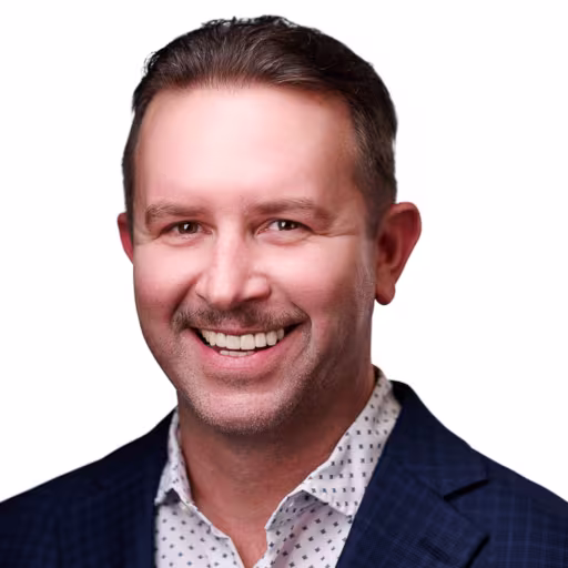 headshot of Jared Heesacker, wearing a dark blue suit with a polka dot shirt