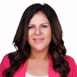 headshot of Jenni Geiger, wearing a pink blazer and a white shirt