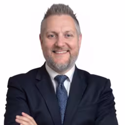 Jerry Buonanno Headshot, wearing a black suit with a blue tie.
