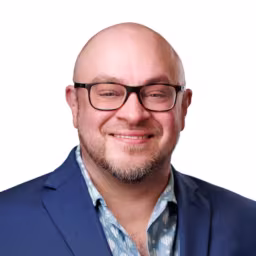 headshot of Jesse Mutarelli, wearing a blue suit