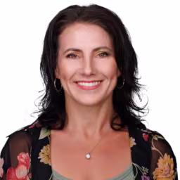 Headshot of Julie Galli wearing sage green under shirt and black floral blouse with white background