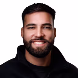 Headshot of Kevin Garcia wearing black shirt and black zip up with white background
