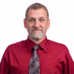 headshot of Matthew Yakich, wearing a red button up with a patterned tie
