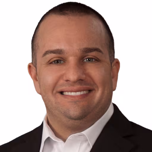 Headshot of Nick Rovella wearing white dress shirt and black suit coat with white background