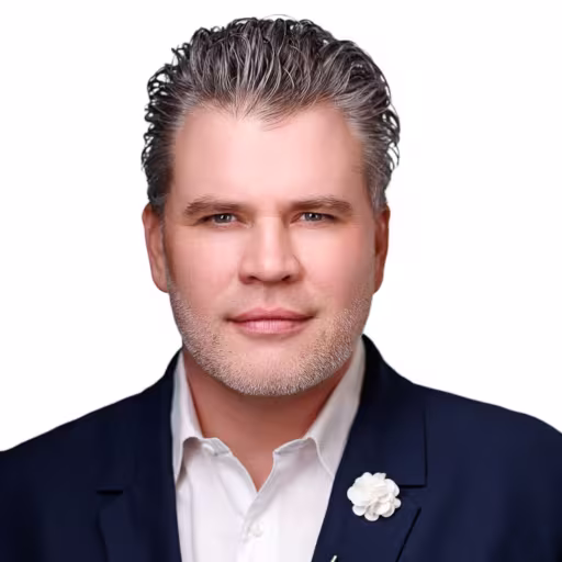 headshot of Patrick Keelin, wearing a black suit with a white shirt