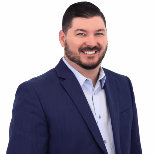 headshot of Ryan Kelly, wearing a dark blue suit with a white shirt