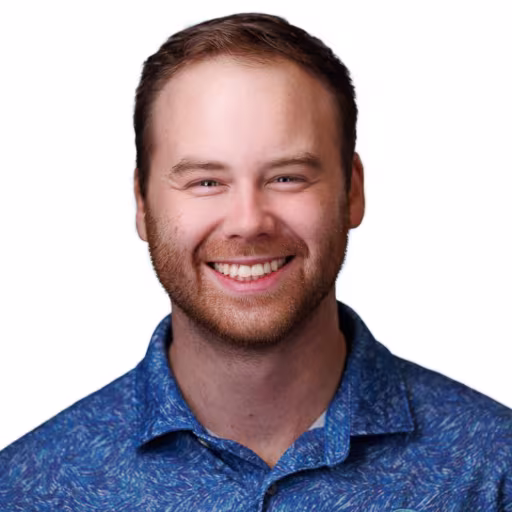 Headshot of Sam Bickle wearing blue button up shirt with white background