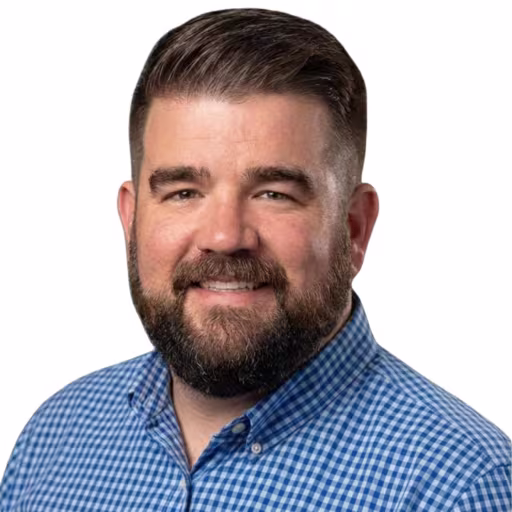 Headshot of Tom Slick, wearing a checker white and blue shirt