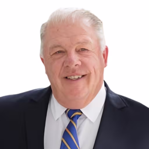 Headshot of Tim Ryan wearing white shirt, blue and gold striped tie, and black suit coat with white background