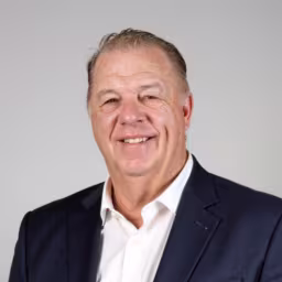 headshot of Tim Ryan, wearing a black suit with a white shirt