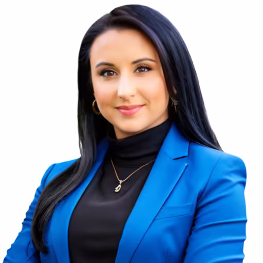 Headshot of Shaina Belles wearing black shirt and blue overcoat with white background