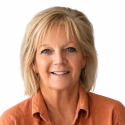 headshot of Sheila Newman, wearing an orange shirt