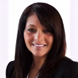 headshot of Gina Talanca, wearing a black blazer and striped shirt