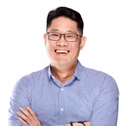 Headshot of Henry Jeong wearing blue and white checkered dress shirt with white background
