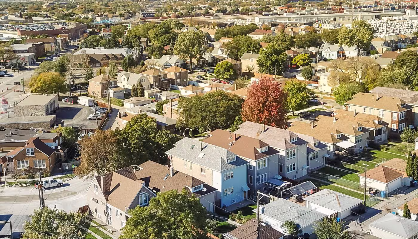 Panorama aerial view traditional residential neighborhood west of Chicago. Row of classic house with garden and detached garage. Skylines from downtown in background