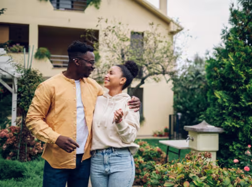 Multiracial couple holding keys and standing outside their new home
