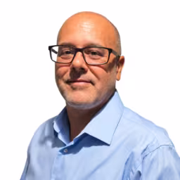 Headshot of David Vasquez wearing light blue button up dress shirt with white background