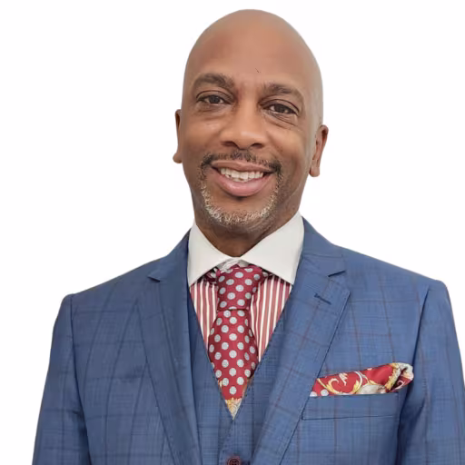 headshot of Marlon Mitchell, wearing a blue suit with a red and white stripped shirt and tie