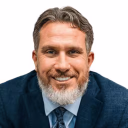 Headshot of Mike Buczynski wearing light blue dress shirt, dark blue tie, and dark blue suit coat with white background