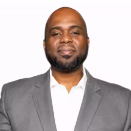 Headshot of Robert Lewis wearing white dress shirt and grey suit coat with white background