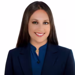 Headshot of Brittney Benjamin wearing blue button up dress shirt and blue suit coat with white background