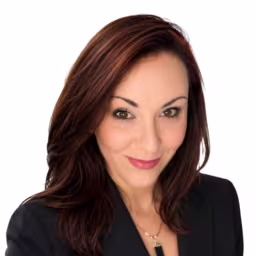Headshot of Kelly Luna wearing black suit coat with white background