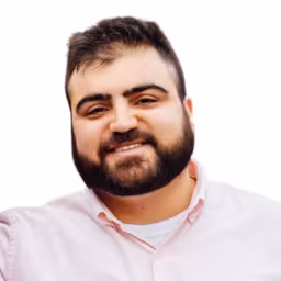 Headshot of Joe Penna wearing light pink button up shirt with white background